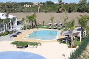 an empty swimming pool with palm trees and umbrellas at AGRITURISMO CASA RICOTTA in Metaponto