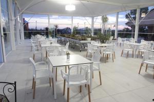 um restaurante com mesas e cadeiras brancas e janelas em AGRITURISMO CASA RICOTTA em Metaponto