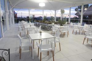 un restaurant avec des tables blanches, des chaises et des fenêtres dans l'établissement AGRITURISMO CASA RICOTTA, à Métaponte