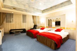 a hotel room with two beds with red sheets at Hotel Liberty Kochi (Adult Only) in Kochi