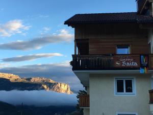 a building with a balcony with a mountain in the background at Garni Baita in San Cassiano