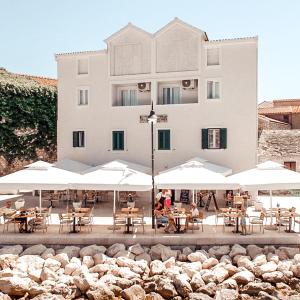een gebouw met tafels en witte parasols bij Guest House Adria in Primošten
