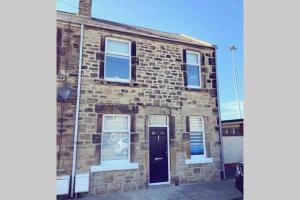 a brick building with a black door on a street at On The Harbour - unrivalled views of Amble's harbour and estuary in Amble
