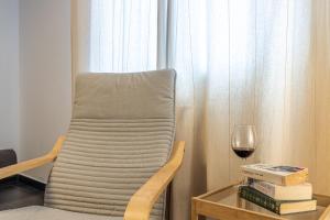 uma cadeira ao lado de uma mesa com um copo de vinho em HOMEABOUT LA MERCED Duplexes em Málaga