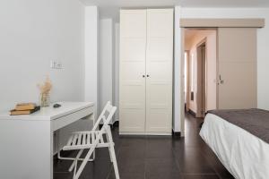 a white bedroom with a desk and a bed at HOMEABOUT LA MERCED Duplexes in Málaga