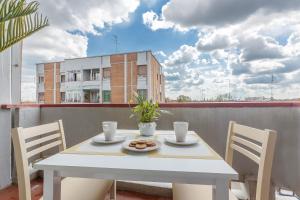 une table et des chaises blanches sur un balcon avec un bâtiment dans l'établissement Luminoso Appartamento con Terrazzo Vicino all'Universita', à Ferrare