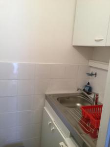 eine Küche mit einem Waschbecken und einem roten Korb daneben in der Unterkunft Résidence Les Pierrettes in Saint-Gilles-Croix-de-Vie