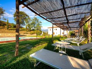 un grupo de mesas bajo una pérgola junto a una piscina en Fattoria Casagrande, en Rignano sullʼArno