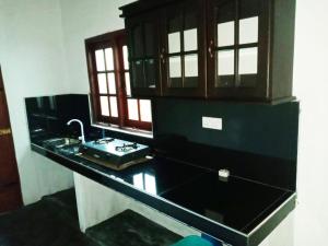 uma cozinha com um balcão preto e um lavatório em Sulashika Beach House em Kandakuli