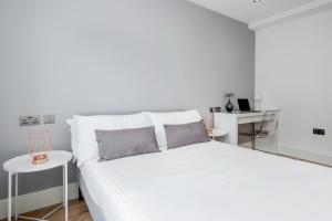 a white bedroom with a bed and a table at Luxury Chic Apartment near Canary Wharf, Excel, O2 & Stratford in London