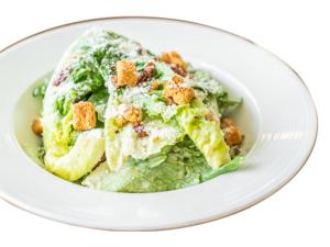 un plato blanco con una ensalada con croutones. en Invito Guesthouse, en Sihanoukville