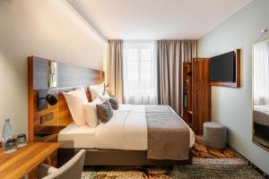 une chambre d'hôtel avec un lit et une télévision dans l'établissement Hotel des Vosges BW Premier Collection, à Strasbourg