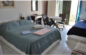 a bedroom with a bed with blue sheets and a table and chairs at Eleni's Studios in Karavostasi