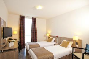 una camera d'albergo con due letti e una televisione di Apparthotel Séjours & Affaires Manosque a Manosque