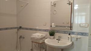 a white bathroom with a sink and a mirror at Alojamiento Árdales in Frailes