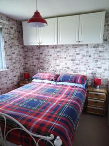 a bedroom with a bed with a plaid blanket and white cabinets at Lighthouse Chalet in Lowestoft