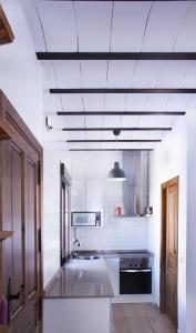 a white kitchen with a sink and a stove at El Loft de Dulcinea: en el corazón de El Toboso. in El Toboso