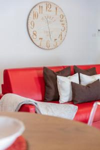 リーヴァ・デル・ガルダにあるRivApartmentsDowntowN Loveの赤いソファ(枕付)、壁掛け時計