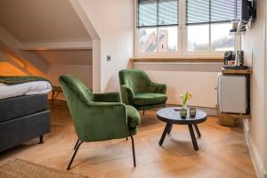 a living room with two green chairs and a table at Bed en Baguette in Burgh Haamstede