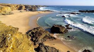 a beach with rocks and the water and the ocean at Casa São Francisco in Porto Covo