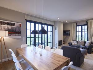a dining room and living room with a table and chairs at Reetland am Meer - Luxus Reetdachvilla mit 3 Schlafzimmern, Sauna und Kamin F11 in Dranske
