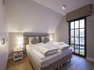 a white bedroom with two beds and a window at Reetland am Meer - Luxus Reetdachvilla mit 3 Schlafzimmern, Sauna und Kamin F11 in Dranske +15 photos