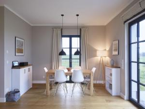 a kitchen and dining room with a table and chairs at Reetland am Meer - Premium Reetdachvilla mit 3 Schlafzimmern, Sauna und Kamin F10 in Dranske
