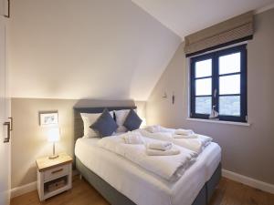 a bedroom with a large white bed with a window at Reetland am Meer - Premium Reetdachvilla mit 3 Schlafzimmern, Sauna und Kamin F10 in Dranske