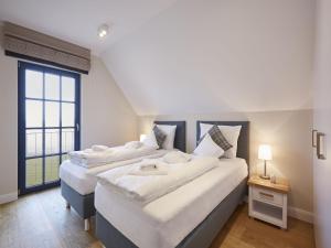 Säng eller sängar i ett rum på Reetland am Meer - Luxus Reetdachvilla mit 3 Schlafzimmern, Sauna und Kamin F08