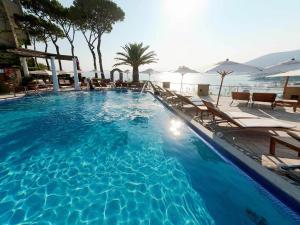 a large blue swimming pool with chairs and umbrellas at San Montano Resort & Spa in Ischia