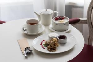 una mesa con un plato de comida y dos tazas de café en Demetra Art Hotel en San Petersburgo