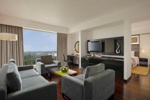- un salon avec un canapé et des chaises dans une chambre d'hôtel dans l'établissement Crowne Plaza Pune City Centre, an IHG Hotel, à Pune