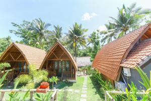 - un complexe avec 2 cottages et des palmiers dans l'établissement Nyuh Gading Bungalow Nusa Penida, à Nusa Penida