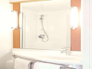 
a white sink sitting under a mirror in a bathroom at ibis Birmingham International Airport – NEC in Bickenhill
