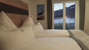 een slaapkamer met een bed met witte kussens en een raam bij Fellhorn Ferienwohnungen in Oberstdorf