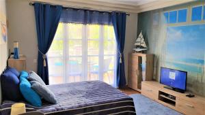 a bedroom with a bed and a tv and a window at Beach House Apartment in Adeje