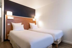 2 letti posti uno accanto all'altro in una stanza di Comfort Hotel ORLY-RUNGIS a Rungis