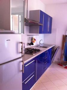 cocina con armarios azules y nevera blanca en Residence Villa Hedy, en San Vincenzo