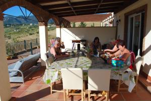 un gruppo di persone seduti intorno a un tavolo su un patio di Bed & Breakfast Finca de los Sueños ad Alhaurín de la Torre