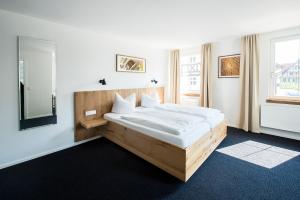 a bedroom with a large bed with a wooden headboard at Stadthotel Waldhorn in Kirchheim unter Teck