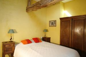 Un dormitorio con una cama con dos almohadas naranjas. en Le Petit Courtoux, en Saint-Germain-en-Coglès