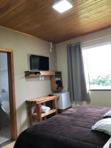 une chambre avec un lit et une télévision à écran plat dans l'établissement Pousada Gianisella, à Bom Jardim da Serra