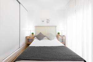 um quarto com uma grande cama branca e duas mesas em Apartamentos Toboso Plaza em Nerja