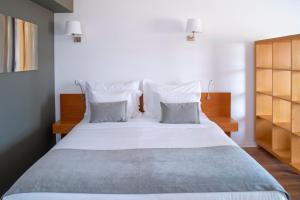 a bedroom with a large bed with white sheets and pillows at Vila Bicuda Resort in Cascais