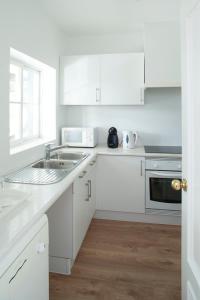 a white kitchen with white cabinets and a sink at Vila Bicuda Resort in Cascais