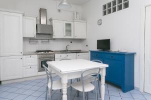 une cuisine avec des placards blancs et une table et des chaises blanches dans l'établissement N006 - Numana, nuovo bilocale nel cuore del paese, à Numana