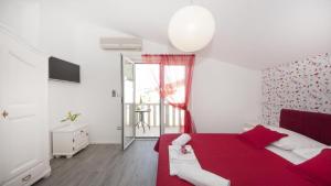 a bedroom with a red bed and a window at Apartments Angela in Baška Voda