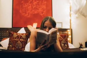a woman laying on a bed reading a book at L'écrin de Rûmi in Vaires-sur-Marne