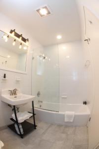 ein weißes Bad mit einem Waschbecken und einer Dusche in der Unterkunft The Surfside Hotel in Stratford