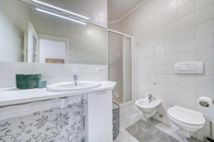 a white bathroom with a sink and a toilet at Zentral gelegenes Apartment mit Garage und Garten in Caldaro